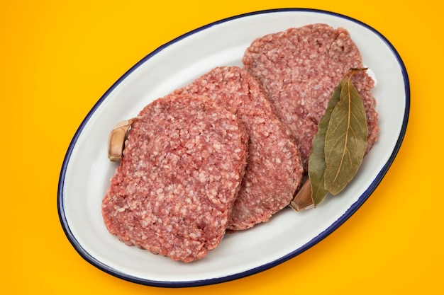 Carne macinata cruda fresca sul piatto bianco con alloro