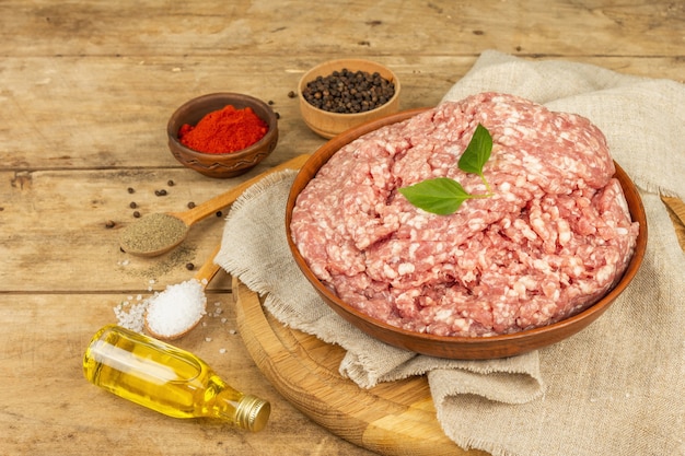 Carne macinata cruda. Maiale macinato con spezie, olio da cucina. Vecchio tavolo in legno, copia spazio