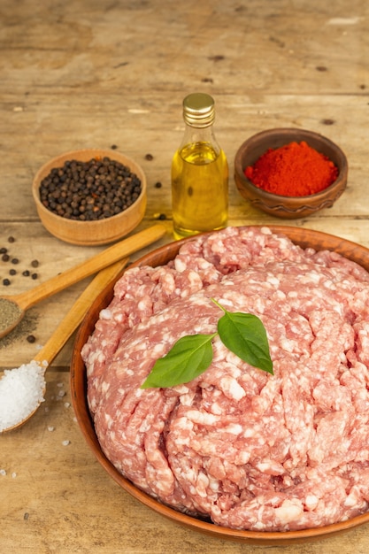 Carne macinata cruda. Maiale macinato con spezie, olio da cucina. Vecchio tavolo in legno, vista dall'alto