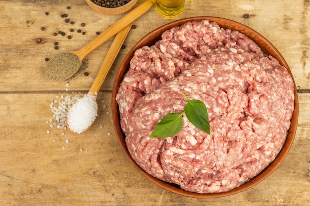 Carne macinata cruda. Maiale macinato con spezie, olio da cucina. Vecchio tavolo in legno, vista dall'alto