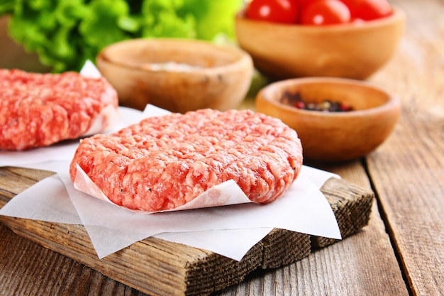 Carne macinata cruda per hamburger fatti in casa grigliati con spazi ed erbe.