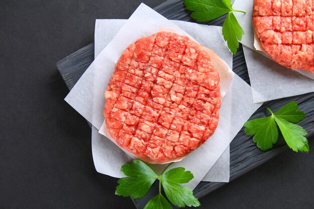 Carne macinata cruda per hamburger fatti in casa grigliati con spazi ed erbe.