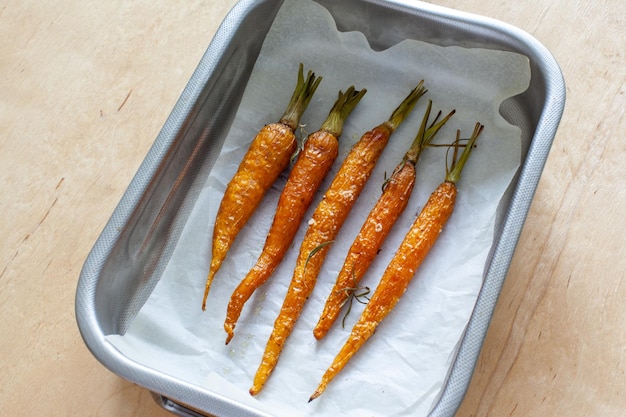 Carota giovane intera arrostita con verdure e sale marino in teglia