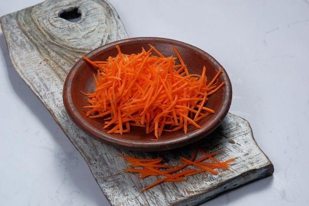 carota grattugiata in una ciotola su sfondo bianco
