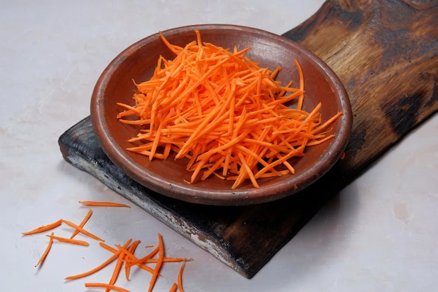 carota grattugiata in una ciotola su sfondo bianco