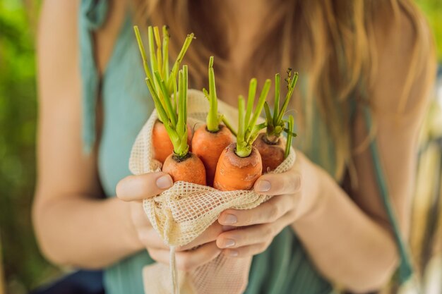 Carota in una borsa riutilizzabile nelle mani di una giovane donna concetto zero rifiuti