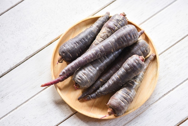 Carota viola sul piatto di legno, carota fresca per cucinare vegetariano sulla tavola di legno