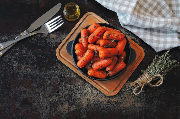 Carotine al forno con erbe aromatiche in una padella di ghisa.