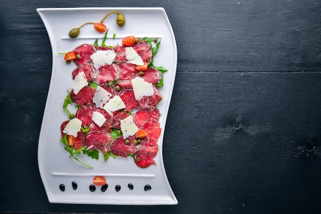 Carpaccio con carne e verdure Cucina italiana Su fondo in legno Vista dall'alto Spazio libero per il testo