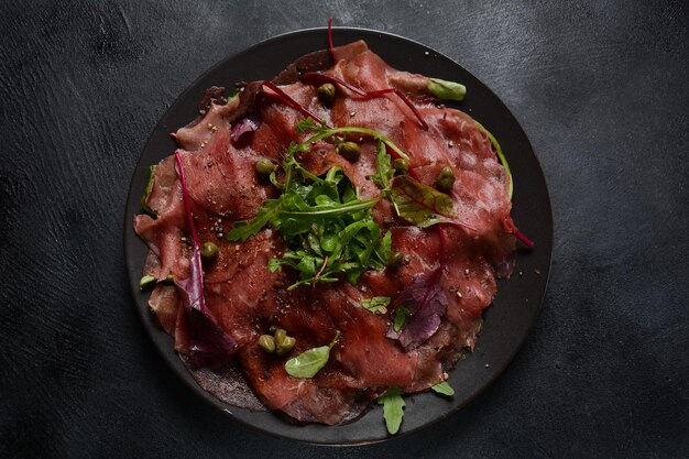 Carpaccio di manzo con parmigiano, capperi e rucola. Con olio d'oliva e salsa di soia