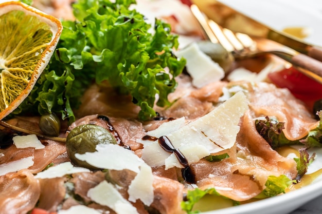 Carpaccio di salmone con capperi, parmigiano e pomodorini. Delizioso concetto di cibo equilibrato.