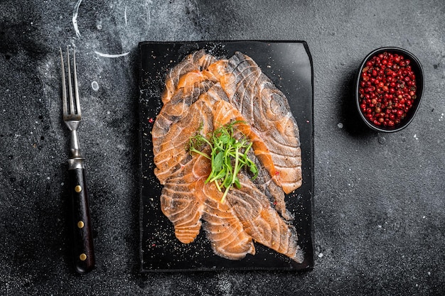 Carpaccio di salmone con microgreens su tavola di marmo Sfondo nero Vista dall'alto