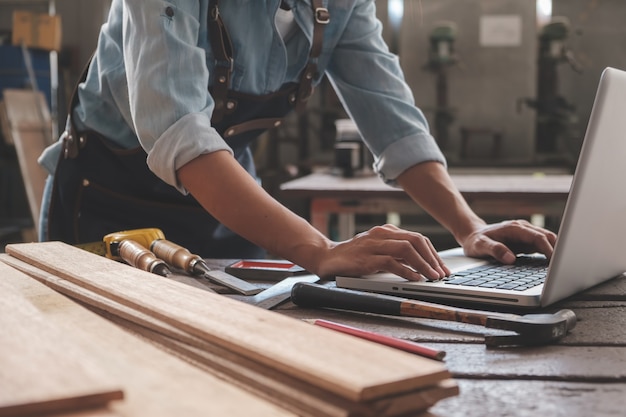 Carpentiere che lavora con l'attrezzatura sulla tavola di legno nel negozio di falegnameria. la donna lavora in una falegnameria.