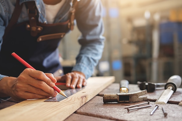 Carpentiere che lavora su macchine per la lavorazione del legno nel negozio di falegnameria.