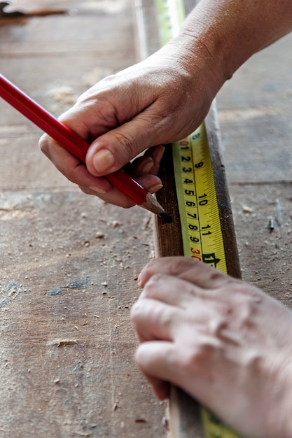 Carpentiere con matita e nastro di misurazione su legno