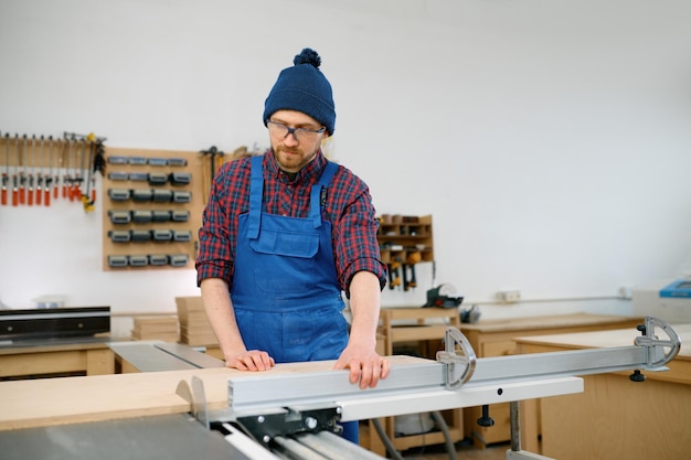 Carpentiere del giovane che lavora alla sega circolare e si è impegnato nella fabbricazione del bianco di legno all'officina