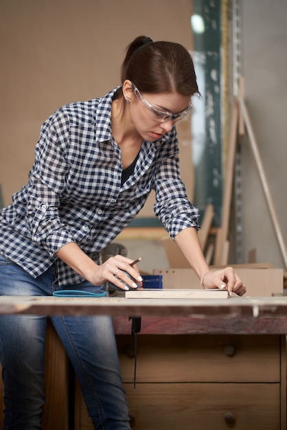 Carpentiere donna con metro a nastro e lavagna in officina