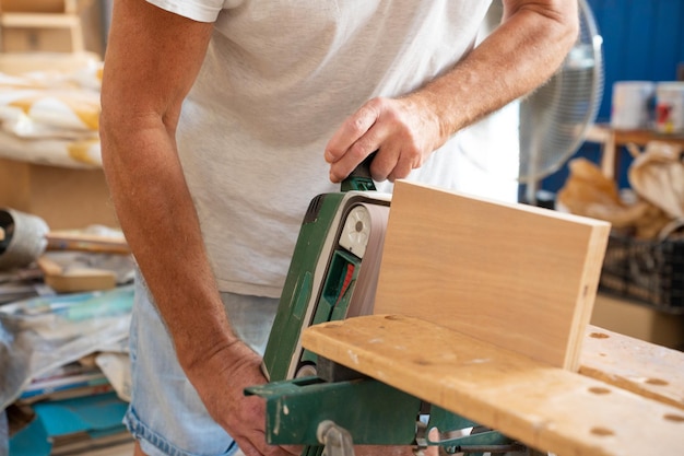 Carpentiere irriconoscibile che lavora su artigianato in legno nell'area di lavoro che produce mobili in legno