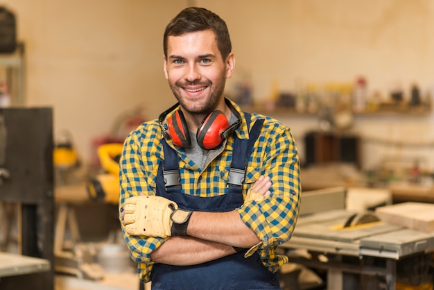 Carpentiere maschio sorridente che sta nell&#39;officina