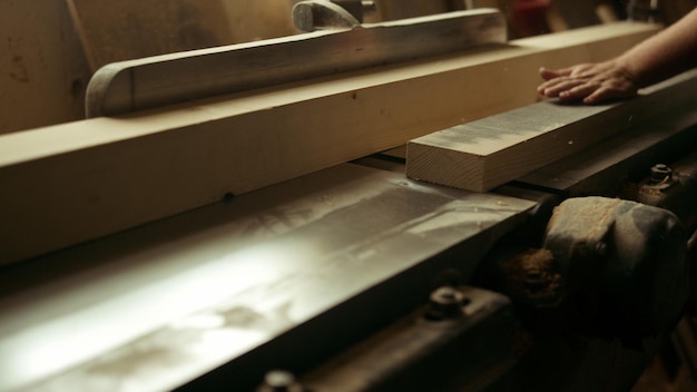 Carpentiere sconosciuto che taglia legno nel laboratorio di falegnameria Primo piano uomo non riconosciuto che prepara tavola in studio Tuttofare che lavora al tornio di legno al chiuso al rallentatore