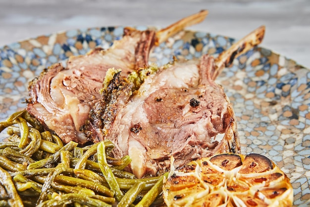 Carrè di agnello al sangue al forno con fagiolini e aglio