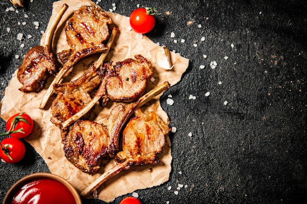 Carrè di agnello alla griglia su carta con salsa di pomodoro e pomodorini