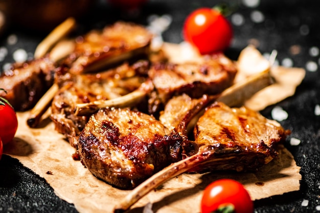 Carrè di agnello alla griglia su carta con salsa di pomodoro e pomodorini