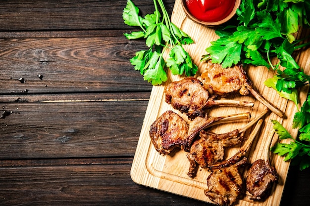 Carrè di agnello alla griglia su un tagliere con salsa di pomodoro e prezzemolo