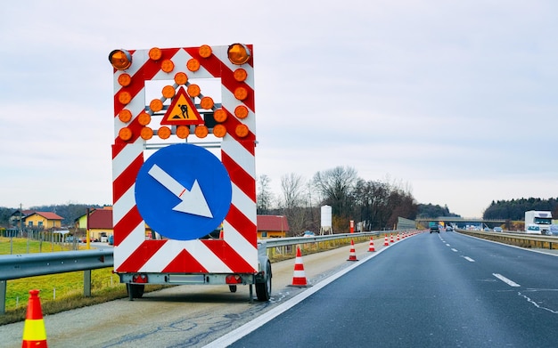 Carreggiata e autocarro con indicatore del segnale stradale durante i lavori stradali. Viaggio di vacanza in strada in autostrada. Bordo dei lavori di costruzione durante la guida. Giro in movimento. Per il trasporto. Corsia sinistra e destra.