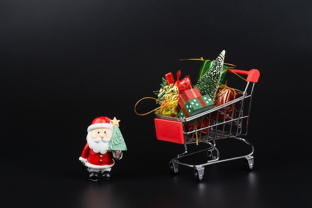 Carrello con albero di Natale e scatole regalo in miniatura e Babbo Natale