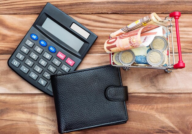 Carrello con calcolatrice in euro e borsa su tavolo di legno Vista dall'alto Concetto di finanza