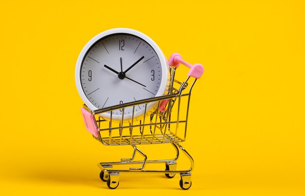 Carrello del supermercato con l'orologio su colore giallo