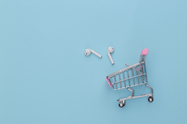 Carrello della spesa con auricolari wireless su sfondo blu.