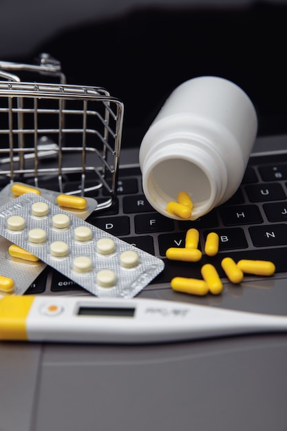 Carrello della spesa con pillole e farmaci sulla tastiera di un laptop. Acquistare medicinali online, acquistare pillole da casa.