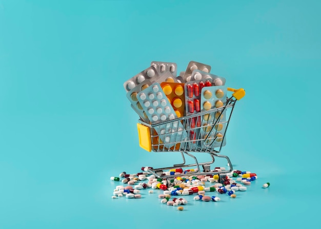 Carrello della spesa con pillole e medicine su sfondo blu