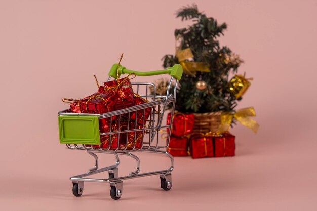 Carrello della spesa natalizia con regali e albero di Natale sullo sfondo