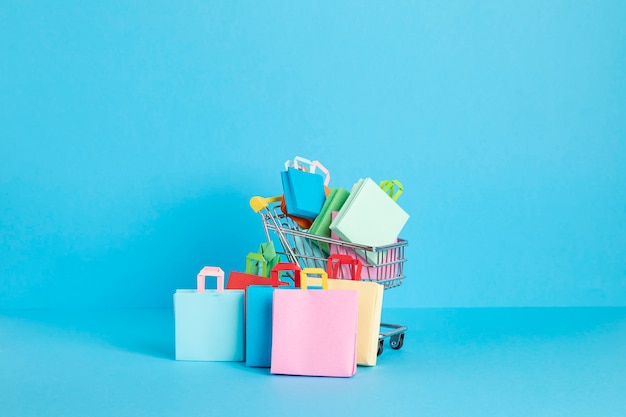 Carrello della spesa pieno di sacchetti di carta shopping concetto di dipendenza