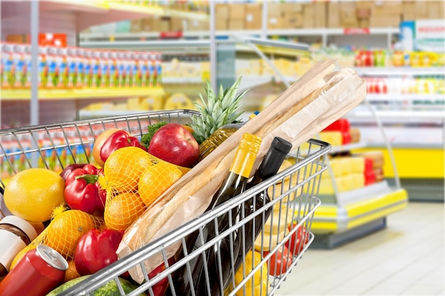 Carrello della spesa pieno di vari generi alimentari in negozio