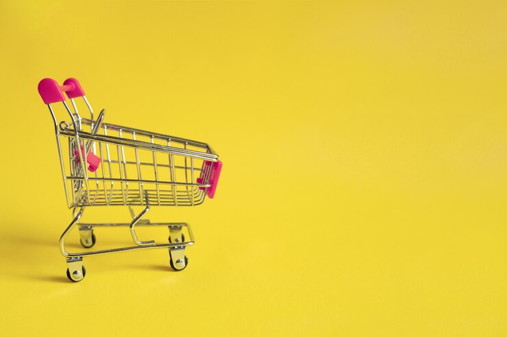 Carrello della spesa vuoto con la maniglia rosa su giallo. Acquisti online . Una forma di commercio elettronico.