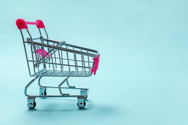 Carrello di spinta del giocattolo della drogheria del piccolo supermercato su fondo blu