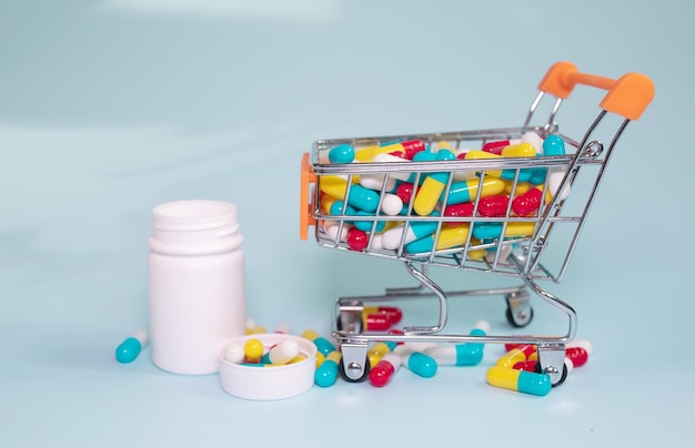 Carrello e pillole su sfondo blu. Il concetto di acquisto di farmaci online.