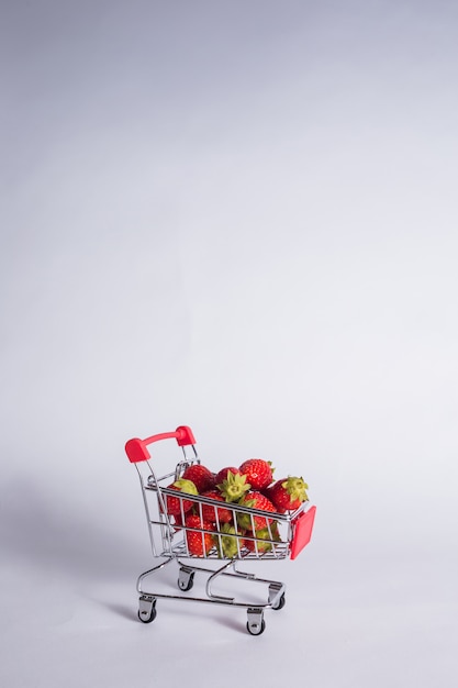 Carrello in metallo con fragole su una stanza isolata bianca