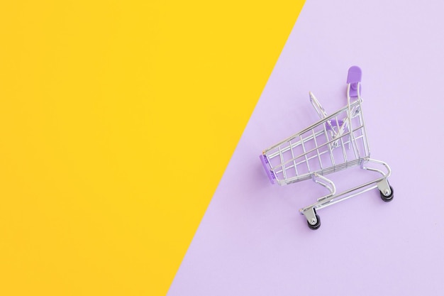 Carrello mini supermercato su sfondo giallo viola