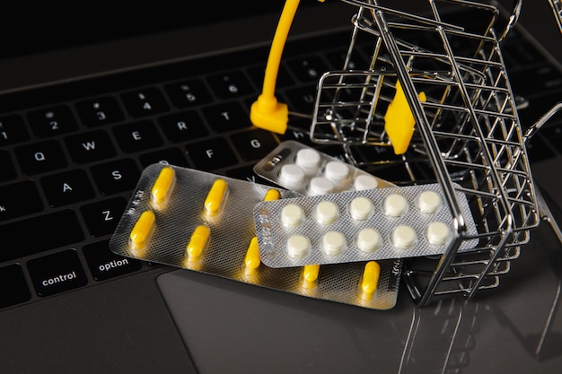 Carrello per farmacia online con pillole su un primo piano della tastiera