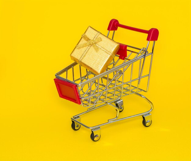 Carrello spesa con regalo oro su sfondo giallo