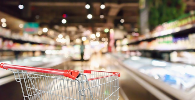 Carrello vuoto con corridoio del supermercato e sfondo sfocato interno degli scaffali dei prodotti