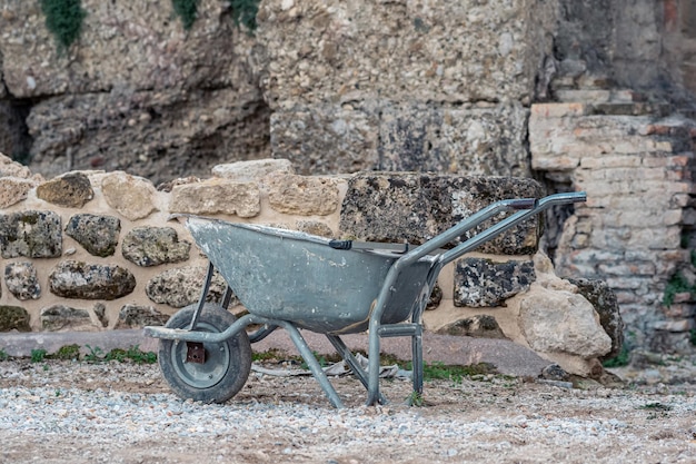 Carriola usata sullo sfondo di antiche rovine di pietra nel sito di scavi archeologici