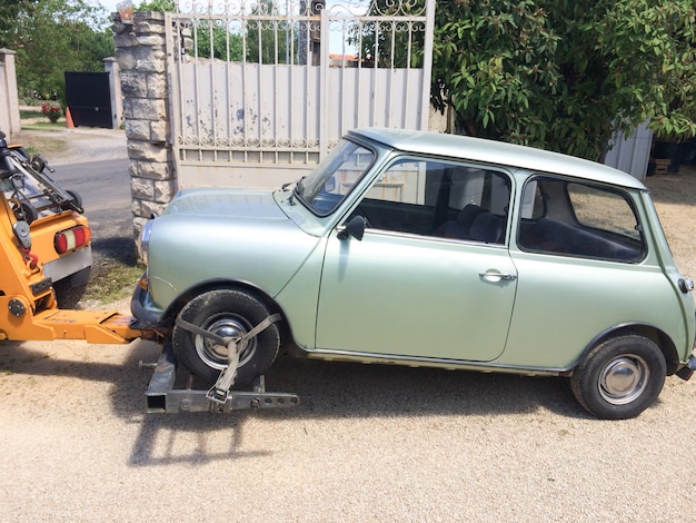 Carro attrezzi che rimorchia una vista della piccola automobile dal camion di assistenza della strada laterale con la mini automobile d'annata