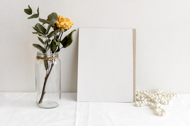 Carta bianca di sfondo di cancelleria alla moda per scritte e rose gialle secche su un tavolo bianco Matrimonio sfondo femminile Vuoto per un biglietto d'invito