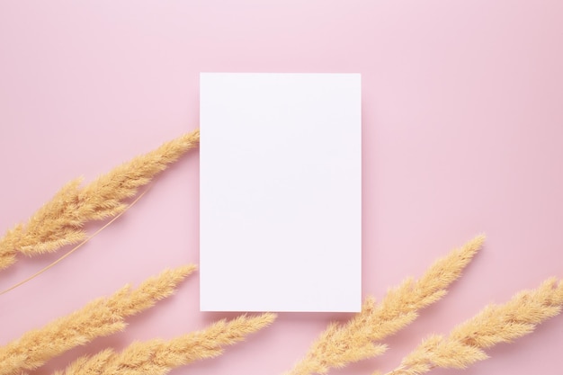 Carta bianca vuota decorazione di erba secca vuota su sfondo rosa Mockup del biglietto d'invito Spazio di copia con vista dall'alto piatto